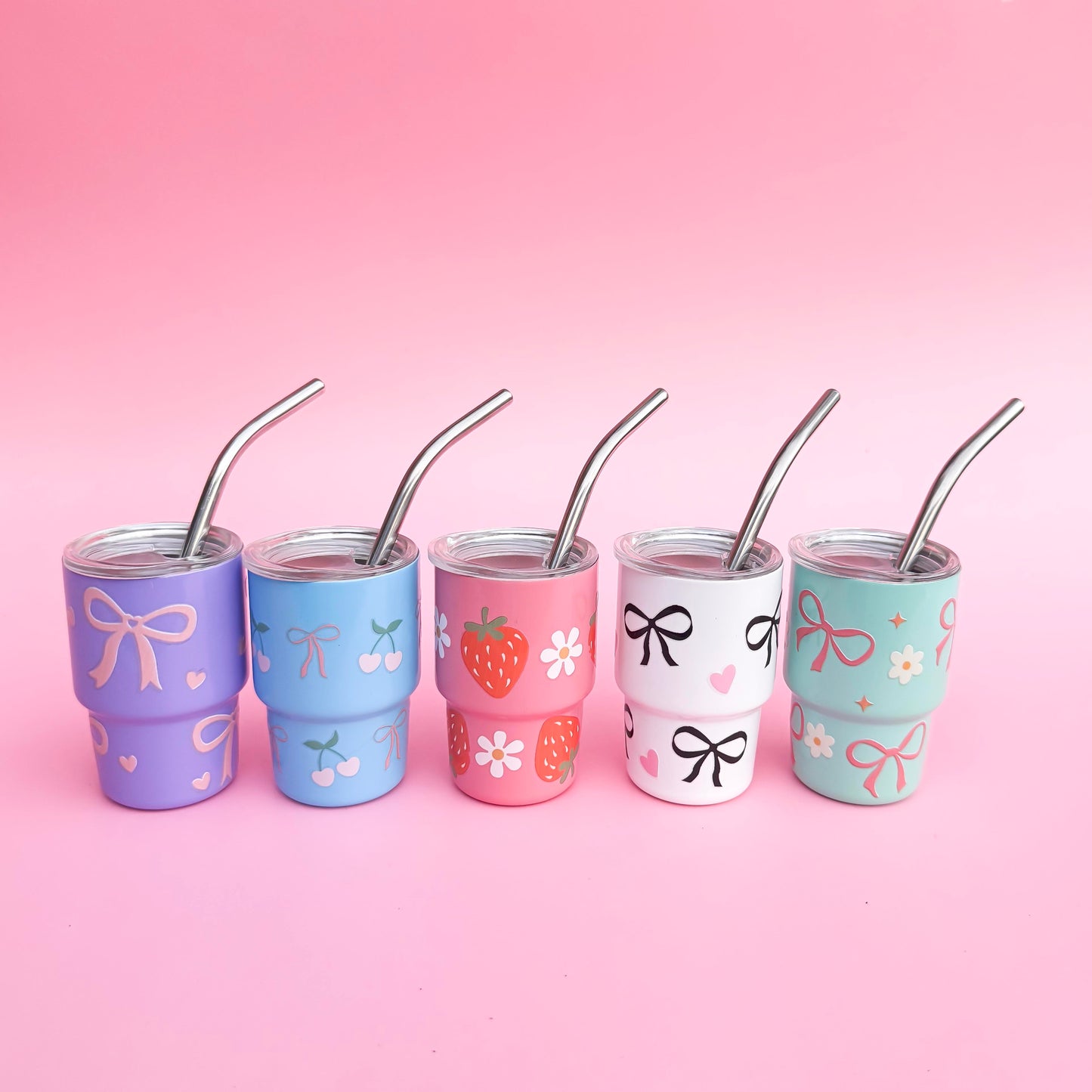 Set of 5 mini 3oz stainless steel tumblers with reusable metal straws, featuring hand-painted pastel designs of bows, hearts, cherries, strawberries, and florals on a pink background