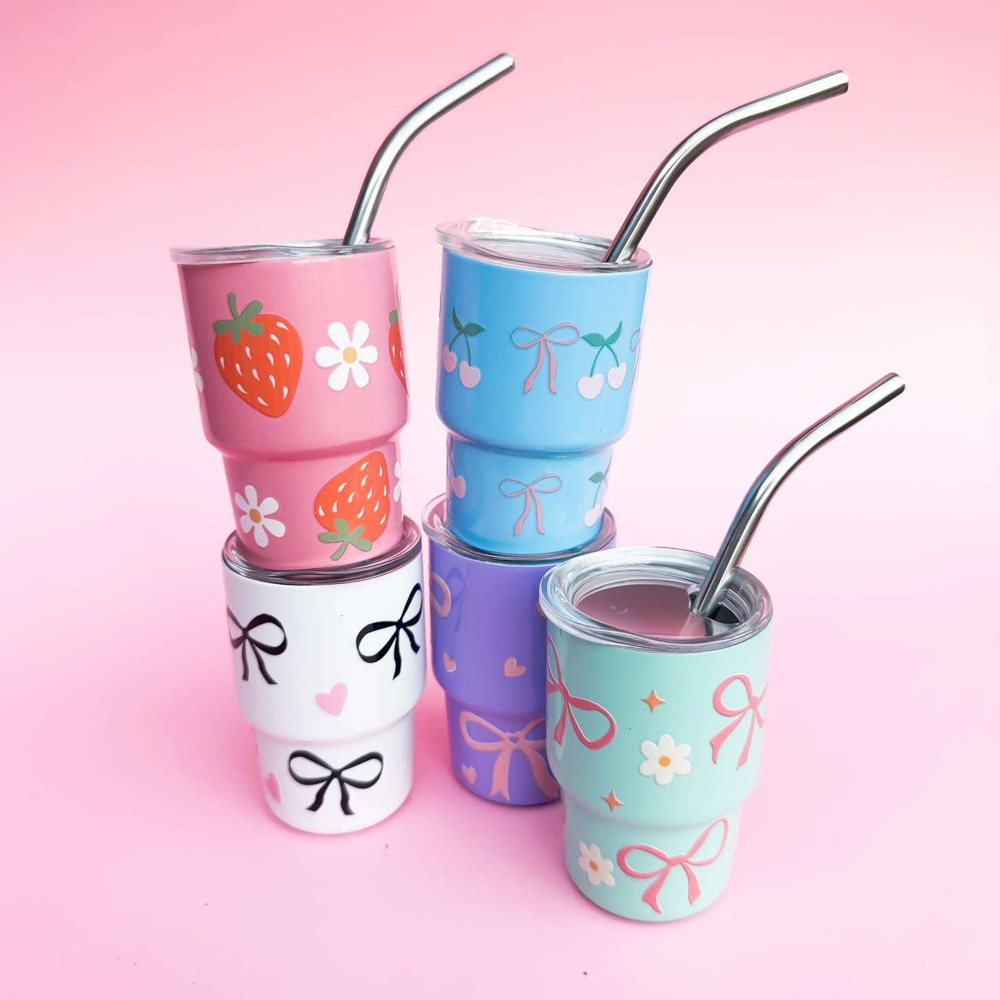 Set of 5 mini 3oz stainless steel tumblers with reusable metal straws, featuring hand-painted pastel designs of bows, hearts, cherries, strawberries, and florals on a pink background