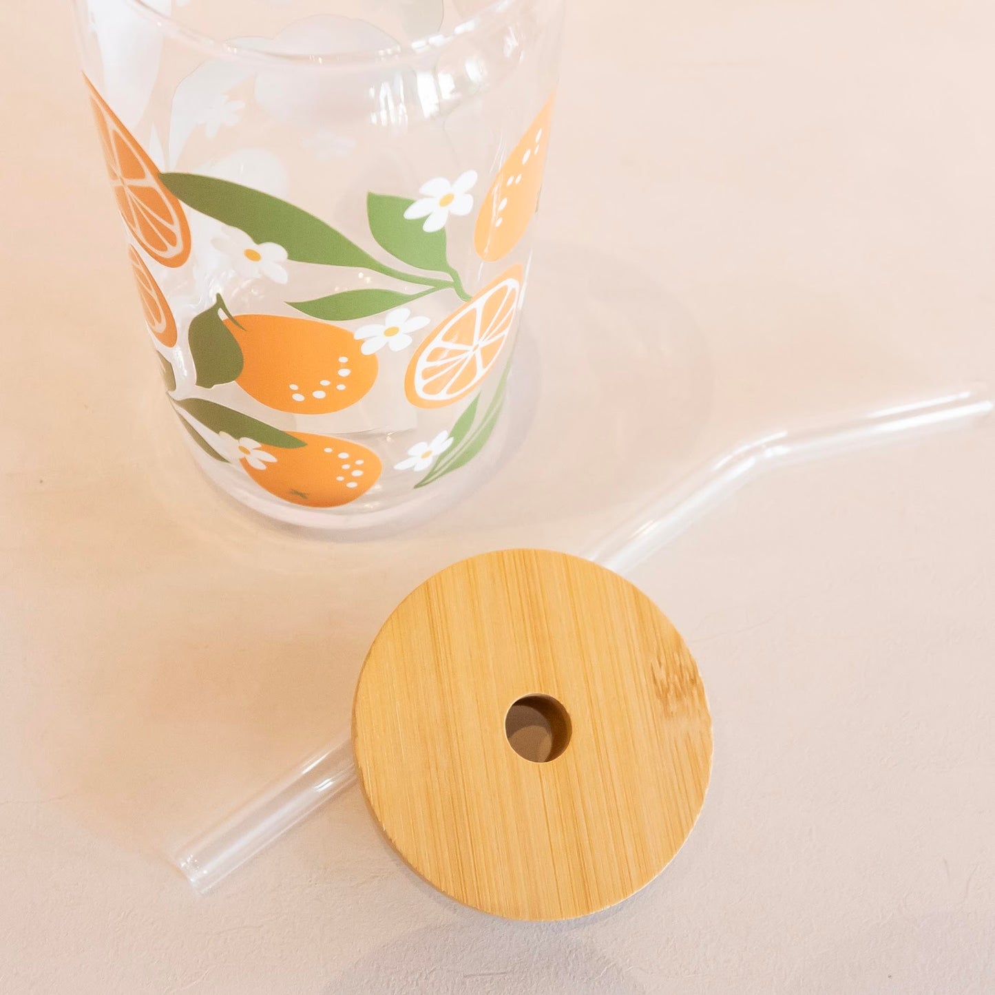 Eco-friendly glass tumbler featuring a vibrant orange blossom design, complete with a bamboo lid and glass straw, perfect for stylish and sustainable hydration