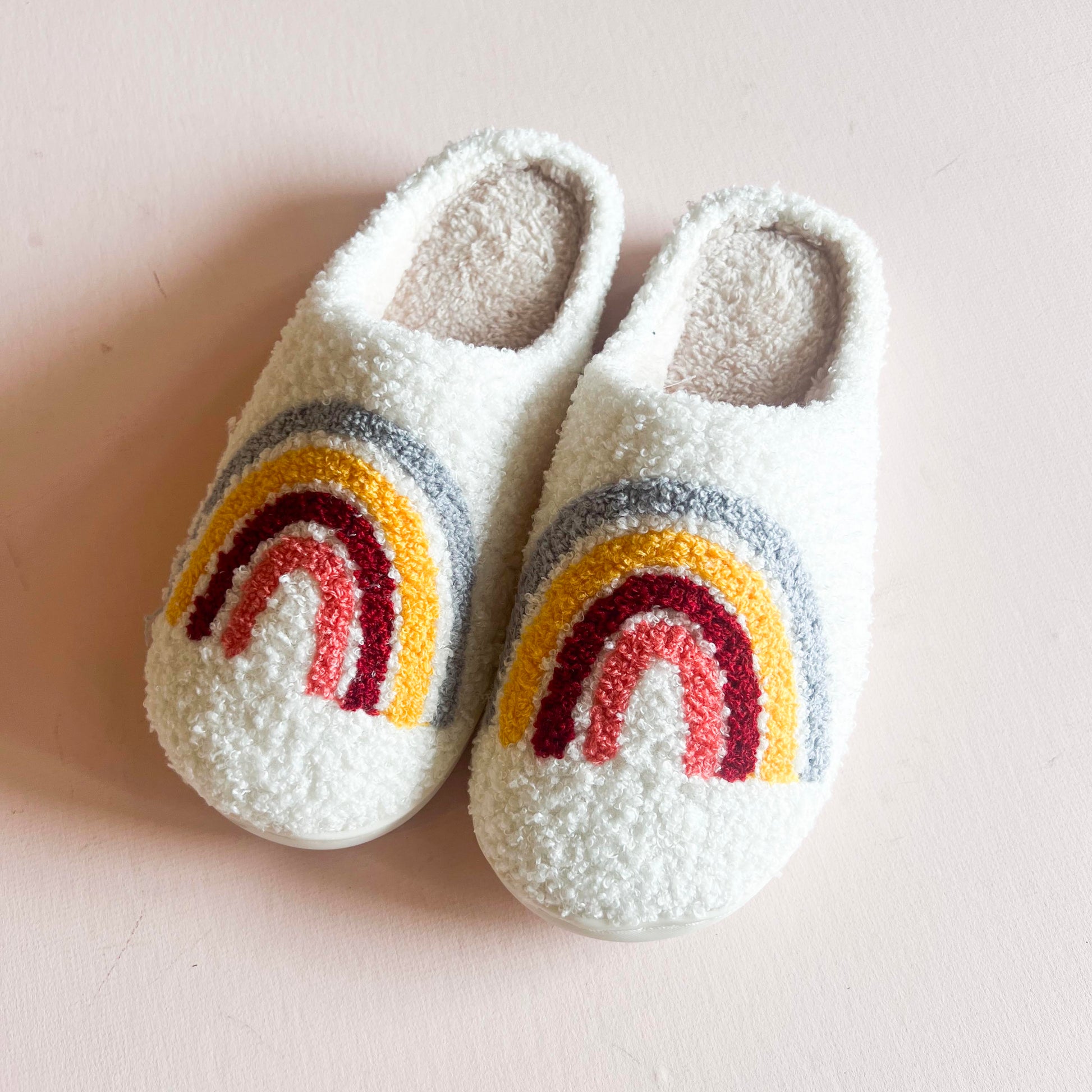 Pair of cozy slippers with a boho-colored rainbow design, featuring soft, warm material and a comfortable fit