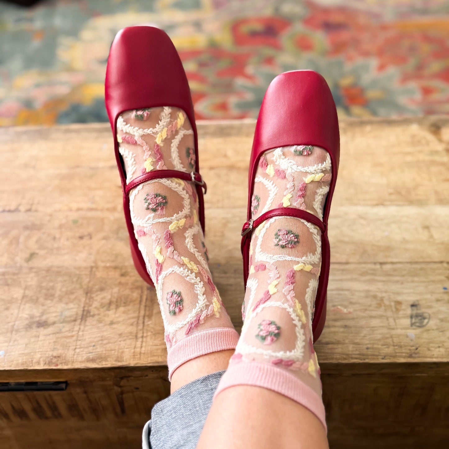 Embroidered vintage-inspired design with soft pink and cream tones worn with a red ballet flat 